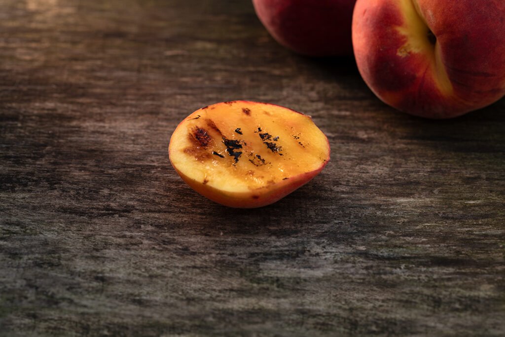 Grilled peach half with charred marks on a 