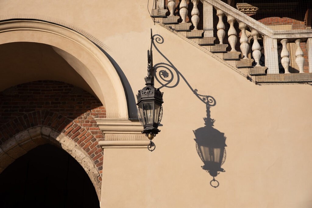 Wrought iron lantern casting a detailed shadow on a beige wall in Kraków's Old Town