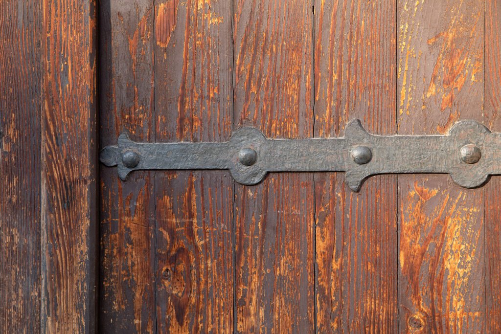 Weathered wooden door with hand-forged iron hinge and rivets, Kraków Old Town