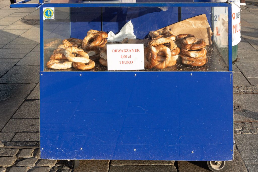 Blue street cart selling obwarzanek krakowski in Kraków, price sign reading 4 zł, 1 euro